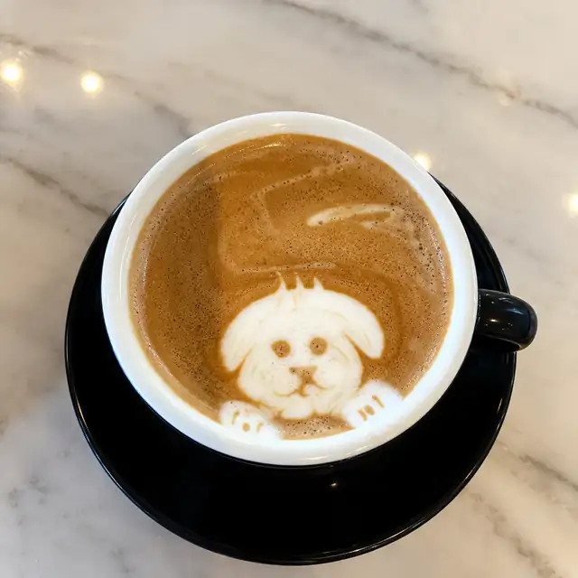 Latte with a puppy drawn in the milk foam, on a marble table.
